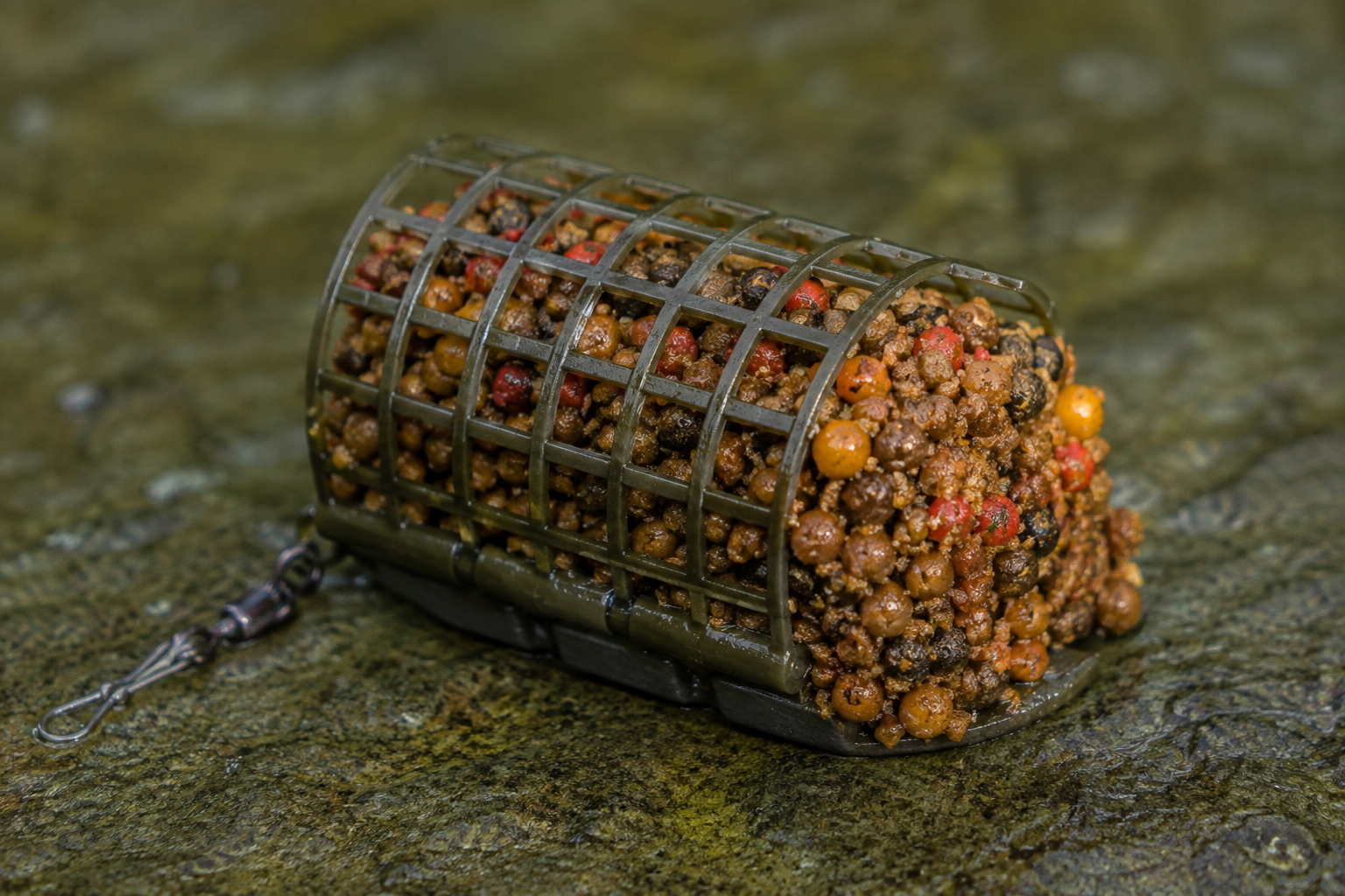 Open ended cage feeder lying on the bottom of a river full with bait.