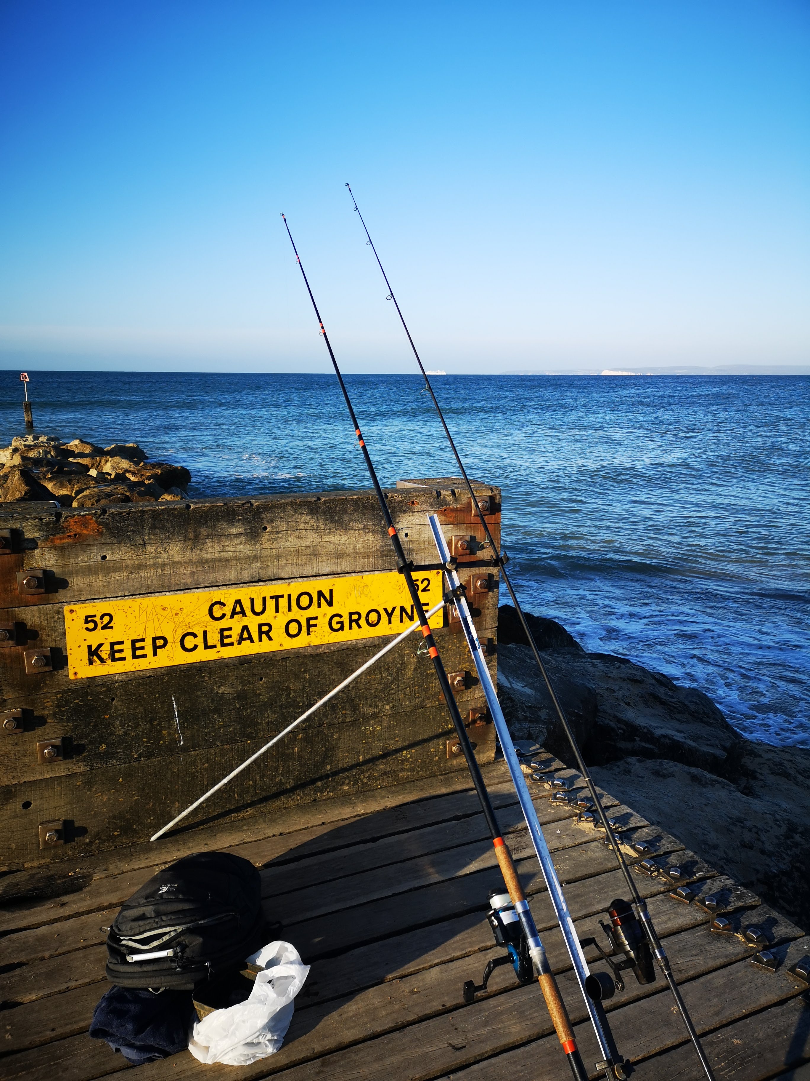 Sea rods on a tripod fishing off a groyne.