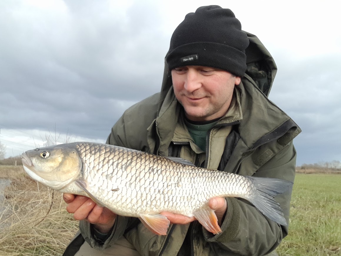 an angler holds a large chub in winter